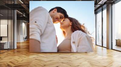 Bottom view close up charming smiling satisfied happy young couple two friends family man woman 20s in white clothes boyfriend hug girlfriend enjoy together touch noses on blue light sky background Wall mural