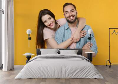 Cheerful laughing young couple two friends guy girl in pastel blue casual clothes isolated on yellow background in studio. People lifestyle concept. Mock up copy space. Hugging, holding hands crossed. Wall mural