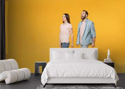 Cheerful young couple two friends guy girl in pastel blue casual clothes posing isolated on yellow background studio portrait. People lifestyle concept. Mock up copy space. Walking, looking aside. Wall mural