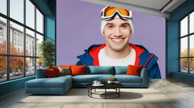 Close up skier man wear warm blue windbreaker jacket ski goggles mask look camera spend extreme weekend winter season in mountains isolated on plain purple background. Hobby concept. Wall mural