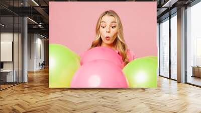 Close up young shocked surprised excited astonished fun woman celebrating birthday holiday looking at bunch of colorful air balloons isolated on plain pastel light pink background. Lifestyle concept. Wall mural