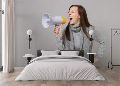 Crazy young woman in gray sweater, scarf scream in megaphone isolated on grey background, studio portrait. Healthy fashion lifestyle, people sincere emotions, cold season concept. Mock up copy space. Wall mural