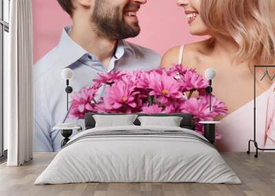 Cropped image of young couple two guy girl in party outfit celebrating posing isolated on pastel pink wall background. Valentine's Day Women's Day birthday holiday concept. Holding bouquet of flowers. Wall mural