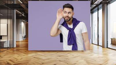 Curious nosy young brunet man 20s wears white t-shirt purple shirt try to hear you overhear listening intently isolated on pastel violet background studio portrait. People emotions lifestyle concept Wall mural