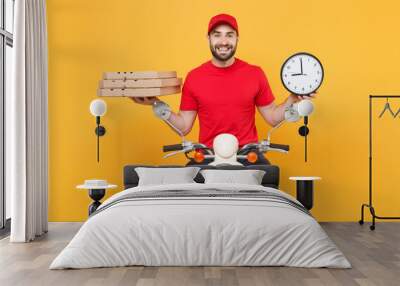 Delivery man in red cap t-shirt uniform driving moped motorbike scooter hold pizza in cardboard clock isolated on yellow background studio Fun guy employee working courier Service quarantine concept Wall mural