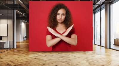 Displeased young african american woman girl in casual t-shirt posing isolated on red background studio portrait. People lifestyle concept. Mock up copy space. Showing stop gesture with crossed hands. Wall mural