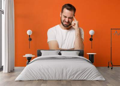 Dissatisfied upset young man in casual white t-shirt posing isolated on orange background studio portrait. People lifestyle concept. Mock up copy space. Put hand on head, keeping eyes closed, crying. Wall mural