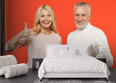 Excited cheerful funny couple two friends elderly gray-haired man blonde woman wearing white pink casual clothes standing showing thumbs up isolated on bright orange color background studio portrait. Wall mural