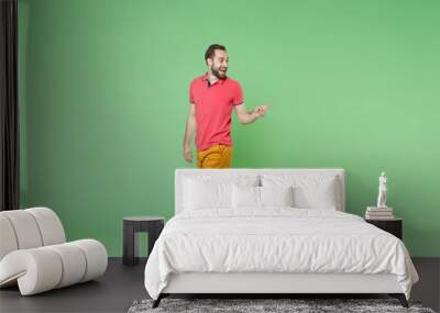 excited young bearded man guy in casual red pink t-shirt posing isolated on green wall background st Wall mural