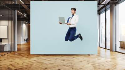 Full body fun sideways young employee IT business man corporate lawyer in classic formal shirt tie work in office hold use laptop pc computer isolated on plain pastel blue background studio portrait Wall mural