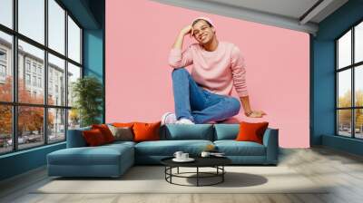 Full body happy young gay man wear sweatshirt hat sitting on floor prop up head forehead look camera isolated on plain pastel light pink color background studio portrait Lifestyle lgbtq pride concept Wall mural