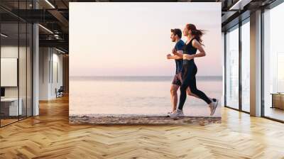 Full body profile couple young two friends strong sporty sportswoman sportsman woman man 20s in sport clothes warm up training run on sand sea ocean beach outdoor jog on seaside in summer day morning. Wall mural