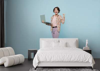 Full body side view young overjoyed excited happy woman 20s wearing brown shirt hold use work on laptop pc computer do winner gesture isolated on pastel plain light blue background studio portrait Wall mural