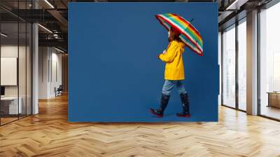 Full body side view young woman in sweater red hat yellow waterproof raincoat hold opened colorful umbrella isolated on plain dark royal navy blue background Outdoors wet fall weather season concept Wall mural