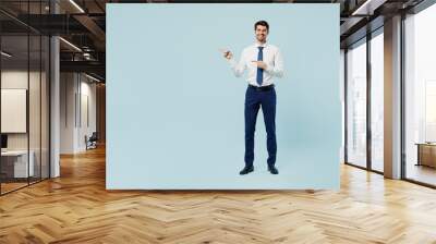 Full body young employee IT business man corporate lawyer wear classic formal shirt tie work in office point index finger aside indicate on area isolated on plain pastel light blue background studio. Wall mural