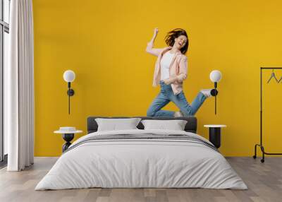 Full body young happy excited singer musician woman she 30s in striped shirt white t-shirt jump high play guitar gesture isolated on plain yellow background studio portrait. People lifestyle concept Wall mural