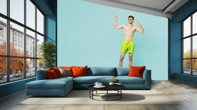 Full body young happy man wear green shorts swimsuit sunglasses relax near hotel pool look aside on area point finger aside isolated on plain blue background. Summer vacation sea rest sun tan concept. Wall mural