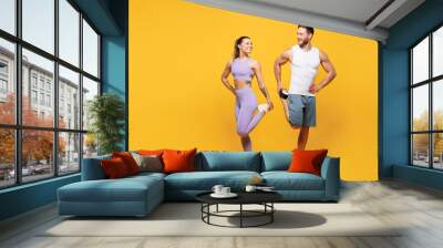 Full body young happy strong fitness trainer sporty two man woman wear blue clothes spend time in home gym do stretch exercise for legs isolated on plain yellow background. Workout sport fit concept. Wall mural