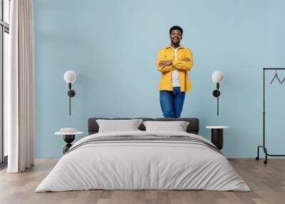 Full body young man of African American ethnicity 20s wear yellow shirt hold hands crossed folded look camera isolated on plain pastel light blue background studio portrait. People lifestyle concept. Wall mural