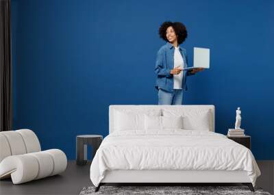 Full body young smiling happy black woman in casual clothes shirt white t-shirt hold use work on laptop pc computer look aside isolated on plain dark blue background studio. People lifestyle concept. Wall mural