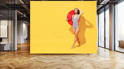 Full length fun happy young sexy woman slim body wear red blue swimsuit pose go with inflatable rubber ring isolated on vivid yellow color background studio Summer hotel pool sea rest sun tan concept Wall mural