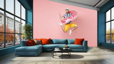 Full length funny traveler tourist man in summer clothes hat jumping hold inflatable ring showing victory sign isolated on pink background. Passenger traveling on weekends. Air flight journey concept. Wall mural