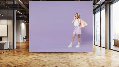 Full length little promoter kid girl 12-13 year old in white shirt hold package purchases shopping bags scream hot news sales hands near mouth isolated on purple background Childhood lifestyle concept Wall mural