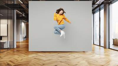 Full length of young excited overjoyed happy lucky positive attractive woman 20s wearing knitted yellow sweater do winner gesture clench fist jumping high isolated on grey background studio portrait.. Wall mural