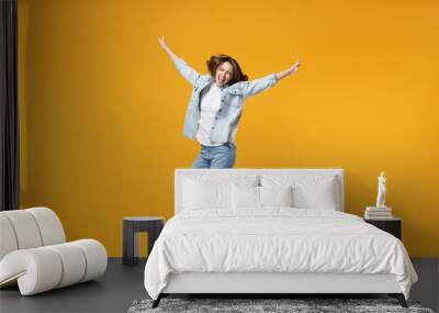 Full length of young overjoyed excited fun expressive student happy woman 20s wearing denim shirt white t-shirt with outstretched hands jump high isolated on yellow color background studio portrait Wall mural