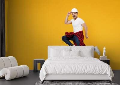 Full length side view young employee handyman man 20s wearing protective helmet jump high run isolated on yellow background. Instruments accessories for renovation apartment room. Repair home concept. Wall mural