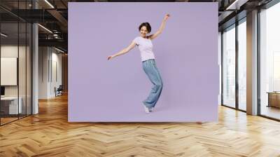 Full length side view young smiling excited cheerful happy woman 20s with bob haircut in white t-shirt leaning back stand on toes dancing have fun isolated on pastel purple background studio portrait. Wall mural