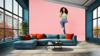 Full size body length young curly latin woman 20s wears casual clothes sunglasses doing winner gesture celebrate clenching fists say yes isolated on plain pastel light pink background studio portrait. Wall mural