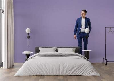 Full size fun young successful employee business man lawyer 20s wears formal blue suit white t-shirt work in office move hand in pocket look aside isolated on pastel purple background studio portrait. Wall mural