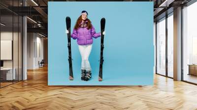 Full size skier happy fun woman in warm purple padded windbreaker jacket goggles mask spend extreme weekend in mountains hld ski look aside on workspace area isolated on plain blue background studio Wall mural