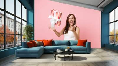 Funny joyful bride woman in elegant white wedding dress screaming throwing up red box with gift present isolated on pink pastel background. Wedding celebration concept. Copy space for advertisement. Wall mural