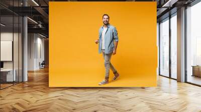 Funny laughing young bearded man in casual blue shirt posing isolated on yellow orange wall background, studio portrait. People sincere emotions lifestyle concept. Mock up copy space. Looking camera. Wall mural