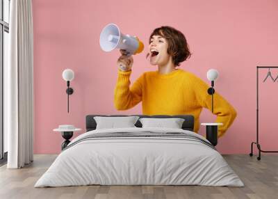 Funny young brunette woman girl in yellow sweater posing isolated on pastel pink wall background studio portrait. People sincere emotions lifestyle concept. Mock up copy space. Screaming in megaphone. Wall mural