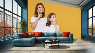 Happy dreamful woman in basic white t-shirt have fun with cute child baby girl 5-6 years old Mom little kid daughter isolated on yellow orange color background studio Mother's Day love family concept Wall mural