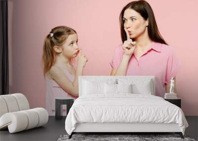 Happy woman wear casual clothes with child kid girl 6-7 years old. Mother daughter say hush be quiet, finger on lips shhh gesture isolated on plain pastel pink background. Family parent day concept. Wall mural