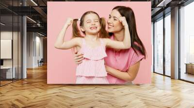 Happy woman wearing casual clothes with child kid girl 6-7 years old. Mother daughter show hand biceps muscles demonstrate strength isolated on plain pastel pink background. Family parent day concept. Wall mural