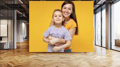 Happy young woman have fun with cute child baby boy 5-6-7 years old in violet t-shirt. Mommy little kid son posing together hugs isolated on yellow background studio. Mother's Day love family concept. Wall mural