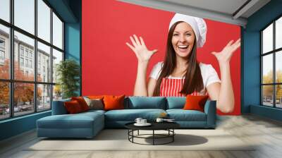 Housewife female chef cook or baker in red striped apron, white t-shirt, toque chefs hat isolated on red wall background. Close up portrait of housekeeper brunette woman. Mock up copy space concept. Wall mural