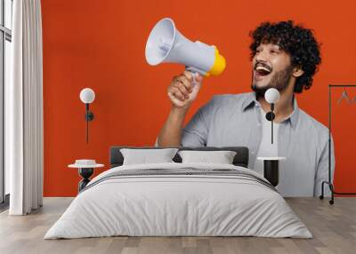 Jubilant overjoyed excited vivid young bearded Indian man 20s years old wears blue shirt hold scream in megaphone announces discounts sale Hurry up isolated on plain orange background studio portrait. Wall mural