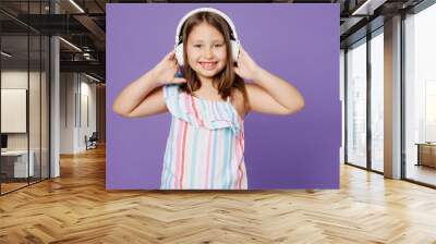 Little smiling happy cheerful kid child girl 5-6 years old wearing striped dress headphones listen music isolated on plain pastel light purple background. Mother's Day love family lifestyle concept. Wall mural