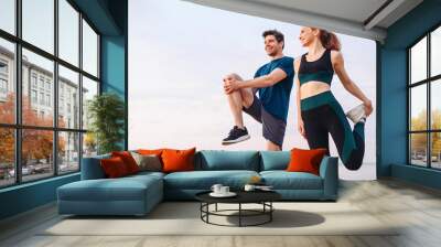 Lower couple young two friend strong sporty sportswoman sportsman woman man in sport clothes warm up training do stretch exercise on sand sea ocean beach outdoor jog on seaside in summer day morning. Wall mural