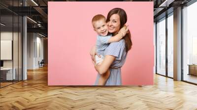 Portrait happy young family. Mother keep in arms, tender embrace, gently hugs child kid son baby boy on pastel pink background. Sincere emotions, fondness, Mother's Day, parenthood, childhood concept. Wall mural