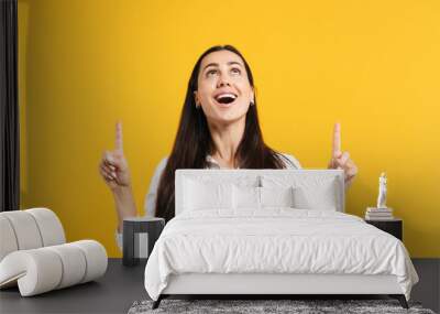 portrait of amazed young woman in white casual shirt keeping mouth open, pointing index fingers up i Wall mural