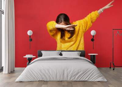 Portrait of young woman in yellow fur sweater with lowered head showing dab dance gesture isolated on bright red background in studio. People sincere emotions, lifestyle concept. Mock up copy space. Wall mural