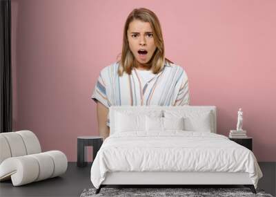 Shocked worried young blonde woman girl in casual striped shirt posing isolated on pastel pink background studio portrait. People emotions lifestyle concept. Mock up copy space. Keeping mouth open. Wall mural