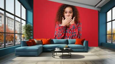 Shocked young african american girl in pajamas homewear posing while resting at home isolated on red wall background. Relax good mood lifestyle concept. Mock up copy space. Covering mouth with hands. Wall mural